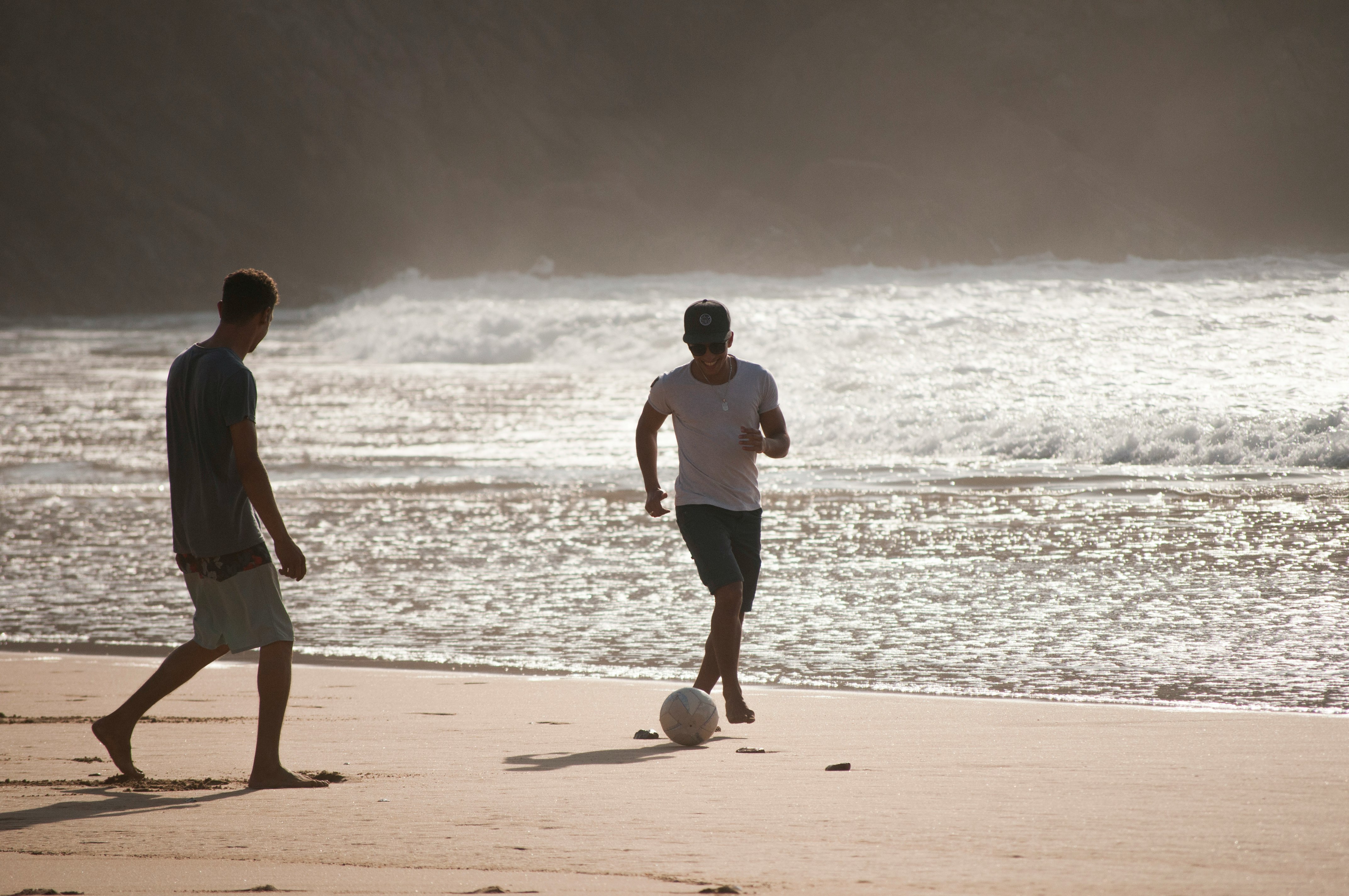 men playing football in beach